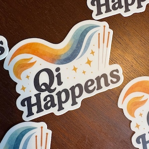 May include: White stickers with the text "Qi Happens" in black, featuring a colourful wave design in orange, blue, and yellow, with gold star accents and acupuncture needles. The stickers are on a brown wooden surface.