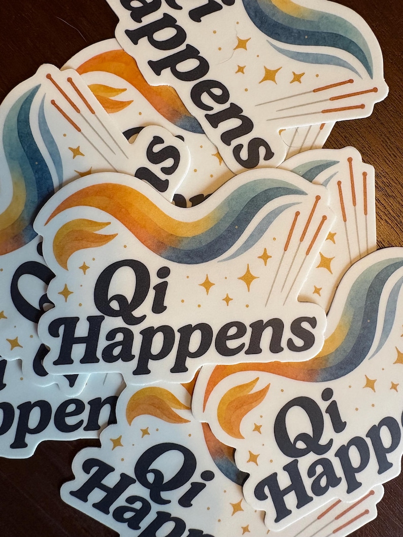 May include: A pile of white stickers with the text "Qi Happens" in black, stylish lettering. Each sticker has a colourful design with orange, blue, and yellow swirls, gold star accents, and acupuncture needles.