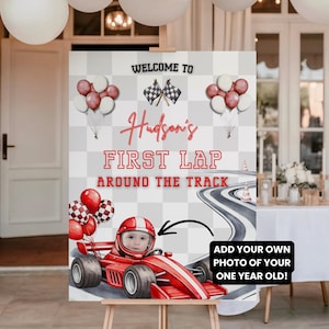 Könnte beinhalten: Willkommensschild für eine Geburtstagsfeier mit Rennwagen-Motiv. Das Schild zeigt ein rotes Rennauto mit einem Baby mit Helm. Der Text lautet "Welcome to Hudson's First Lap Around the Track". Das Schild steht auf einer hölzernen Staffelei.