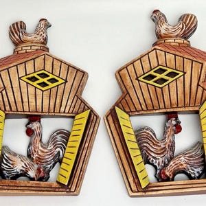 Peut inclure: Paire de décorations murales vintage en bois représentant un coq et une poule dans un cadre en forme de grange. Les cadres sont bruns avec des accents jaunes et rouges, et chacun a un coq au sommet. Un charmant article de décoration de ferme.