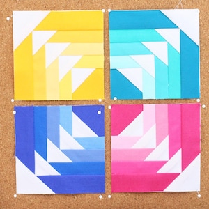 May include: A corkboard displays four colorful quilt blocks in yellow, teal, blue, and pink, each with a geometric design. A black cat-shaped ruler and wooden cat-shaped measuring tool are on the left. Spools of thread in various colors are on the right.