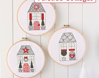 May include: Three white embroidery hoops with red and gray fabric depicting Christmas cottages. The hoops are hanging on a white wall. The text "Yuletide Cottages" is at the top of the image. The text "a SPOONFUL of Sugar make.bake.create." is at the bottom of the image.