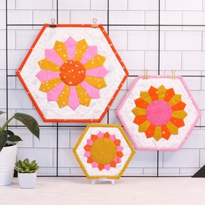 A set of three Dresden placemats. Placemat are hexagon shaped and are small, medium and large. They feature a big, bright, colourful dresden plate in the centre.