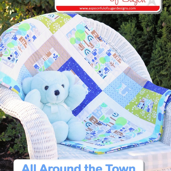 Può includere: Un orsacchiotto blu è seduto su una sedia di vimini bianca, sotto una trapunta patchwork con motivi blu, verdi e bianchi. La trapunta presenta disegni a tema cittadino. Il testo "All Around the Town" è visualizzato in basso.