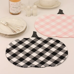 May include: Two pumpkin-shaped placemats, one black and white gingham and one pink and white gingham.