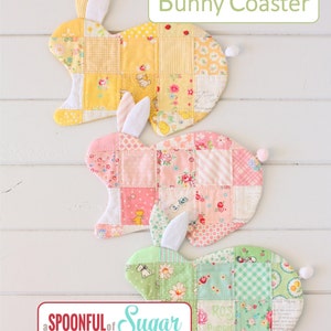 Könnte beinhalten: Drei Hasen-förmige Untersetzer aus Patchwork-Stoff. Die Untersetzer sind gelb, rosa und grün mit floralen und karierten Mustern. Die Untersetzer sind mit "Bunny Coaster" betitelt und stammen von der Marke "a SPOONFUL of Sugar: make. bake. create."