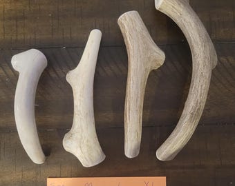 May include: Four natural antler chews for dogs, varying in size from small to extra-large. The sizes are labeled as SM, M, L, and XL, with corresponding length measurements in inches. The sizes are 4-6", 5-6", 6-7", and 8-10".