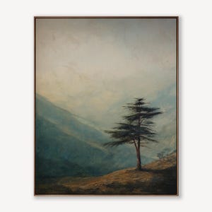 May include: An oil painting of a mountain landscape with a lone tree. The artwork features a muted color palette of blues, greens, and browns, with a focus on the tree's silhouette against the misty mountains. The painting is framed in a simple, dark wood frame.