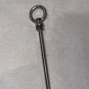 May include: A stainless steel eye bolt with a threaded shaft. The bolt features a circular eye at the top, a nut, and a long, threaded rod. The M8 marking is visible on the nut.