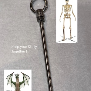May include: A silver-colored metal M8 eye bolt with a long threaded shaft. The image includes text that reads Keep your Skelly Together! and Wyvern too!, along with small inset images of a standing skeleton and a green dragon-like wyvern figure.