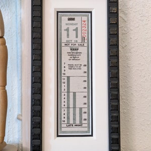 May include: A framed vintage transit ticket from Monday, October 10th, with the number 11 printed on it. The ticket has a black and white design with the words "NOT FOR SALE" and "KEEP THIS TRANSFER/FARE RECEIPT AS PROOF OF PAYMENT" printed on it. The ticket also has a chart with numbers 7 through 10 and times :00 and :30 printed on it.