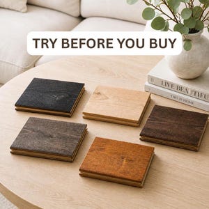 May include: Five square wooden coasters in various wood tones: black, light brown, medium brown, dark brown, and orange-brown. The coasters are arranged on a light brown table. The text "TRY BEFORE YOU BUY" is at the top.