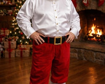 May include: A Santa Claus costume featuring a long-sleeved white satin button-down shirt with gold buttons, red velvet trousers with white faux fur trim at the cuffs, a black belt with a gold buckle, and a red velvet hat with white faux fur trim.