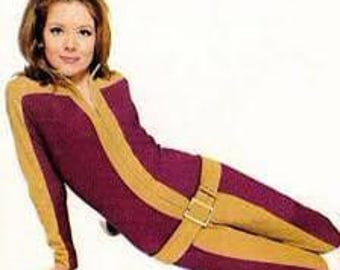 May include: A long-sleeved, full-length jumpsuit featuring a deep burgundy color with contrasting tan panels running down the center, along the sleeves, and across the hips. The garment includes a front zipper and a wide tan belt with a gold buckle.