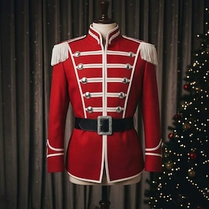 May include: A red military-style jacket featuring white piping, silver-toned buttons, and white fringe epaulets on the shoulders. The jacket is cinched at the waist with a black belt that has a large, rectangular silver-toned buckle at the center.