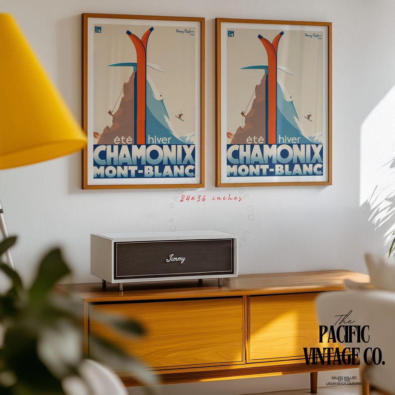 May include: Two framed vintage travel posters, each featuring a ski scene with the text "CHAMONIX MONT-BLANC". The posters are 24x36 inches and are mounted on a white wall. Below, a white and brown speaker with the name "Jimmy" sits on a wooden cabinet.