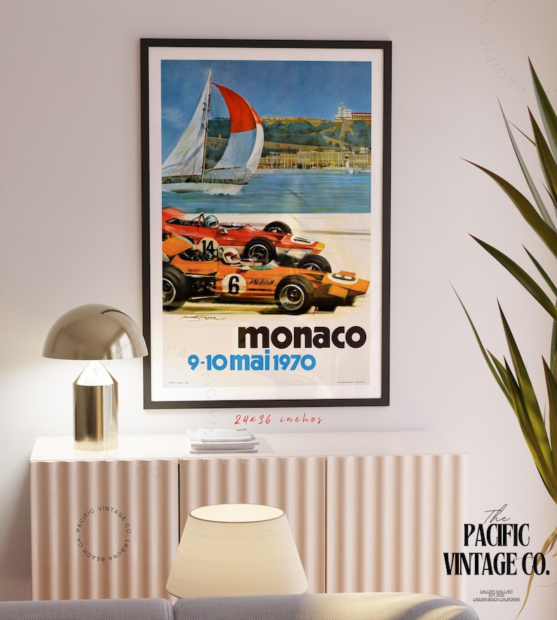 May include: Framed vintage Monaco Grand Prix poster. The poster features two race cars in orange and red, a sailboat, and the text "Monaco 9-10 mai 1970". The poster measures 24x36 inches.