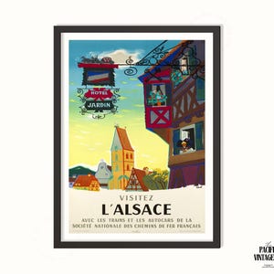 May include: Framed vintage travel poster for Alsace, France, featuring a colorful illustration of a quaint village with a church and half-timbered buildings. The poster includes the text "VISITEZ L'ALSACE" and "HOTEL JARDIN."