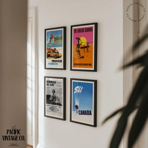 May include: Four framed vintage travel posters on a white wall. Posters include images of a sailboat race, surfers, skiing in Canada, and a surfing event. The posters are in black frames and feature vibrant colors.
