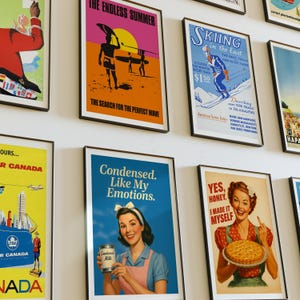 May include: A collection of framed vintage travel and advertisement posters. The posters feature colorful designs and text, including themes of surfing, skiing, and travel to Canada. The posters are displayed on a white wall.