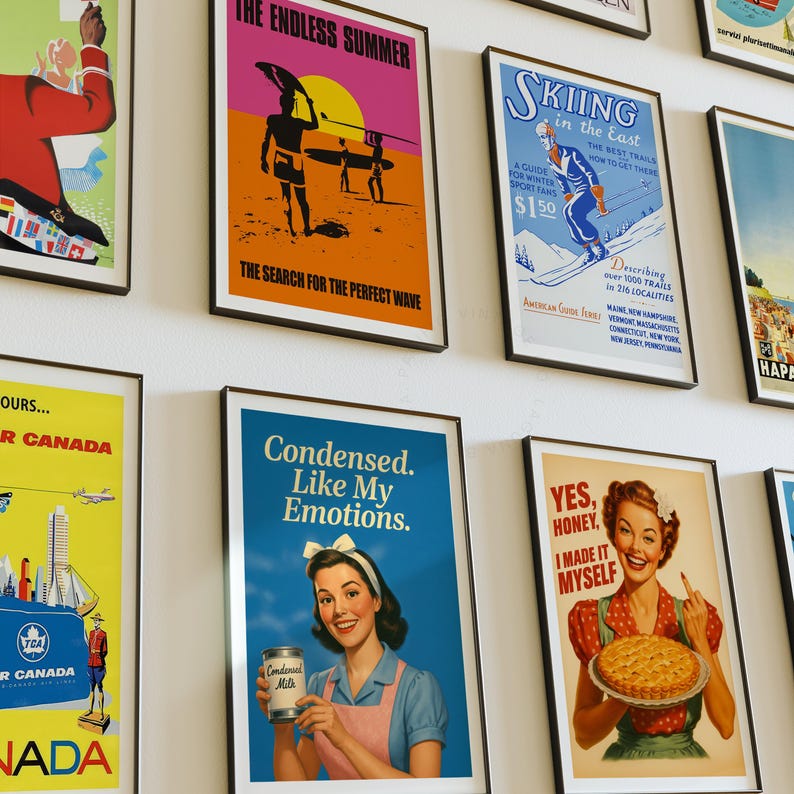 May include: A collection of framed vintage travel and advertisement posters. The posters feature colorful designs and text, including themes of surfing, skiing, and travel to Canada. The posters are displayed on a white wall.