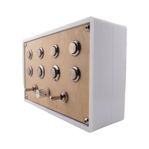 May include: A white rectangular box with a light brown panel featuring multiple silver buttons and toggle switches. The box has a clean, modern design, with a focus on the metallic and neutral color palette.