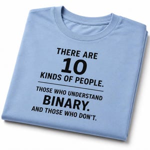 Puede incluir: Una camiseta azul claro con el texto "THERE ARE 10 KINDS OF PEOPLE. THOSE WHO UNDERSTAND BINARY. AND THOSE WHO DON'T." en negro. La camiseta está doblada sobre un fondo blanco.