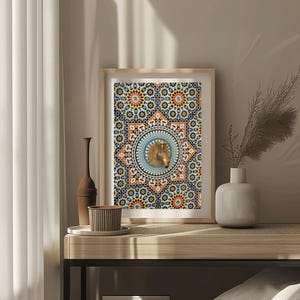 May include: Framed artwork with a mosaic pattern in blue, orange, and gold. The central design features a lion's head. The artwork is displayed on a wooden table with decorative items, including a vase and a cup.