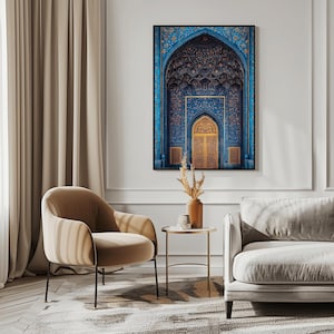 Peut inclure: Une impression encadrée d'une arche bleue et dorée ornée, probablement une entrée de mosquée ou de palais. L'œuvre présente des motifs complexes et une porte dorée. L'impression est accrochée à un mur blanc, avec une chaise beige, un canapé et une table d'appoint au premier plan.