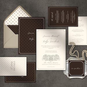 May include: A wedding invitation suite featuring dark brown and cream paper cards with elegant script text. The set includes an envelope with a patterned liner, a main invitation with a building illustration, and detail cards. A string of pearls rests nearby.
