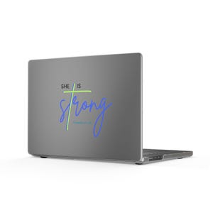 Può includere: Un computer portatile grigio scuro con un adesivo sul coperchio che riporta il testo "SHE IS" in nero, una croce verde lime, la parola "strong" in corsivo blu e il testo blu più piccolo "Proverbs 31:25" centrato sulla superficie.