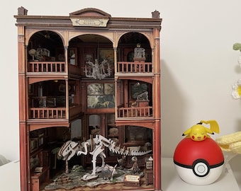 May include: A three-story cardboard fossil museum model with arched balconies and a dinosaur skeleton display, a red and white spherical toy with a yellow character on top, and a bouquet of white, yellow, and light blue crocheted flowers.