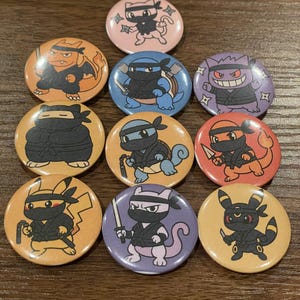 May include: A collection of nine round pinback buttons featuring various cartoon characters dressed as ninjas. The buttons have a variety of colors, including orange, blue, purple, and yellow. Each button has a unique character design.