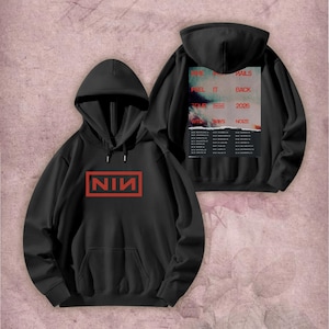 May include: Black hoodie with a red NIN logo in a rectangular frame on the front. The back of the hoodie features a tour poster with the text "WE WILL HAILS FEEL IT BACK TOUR NIN 2026" and a list of tour dates. The hoodie has a hood and a front pocket.