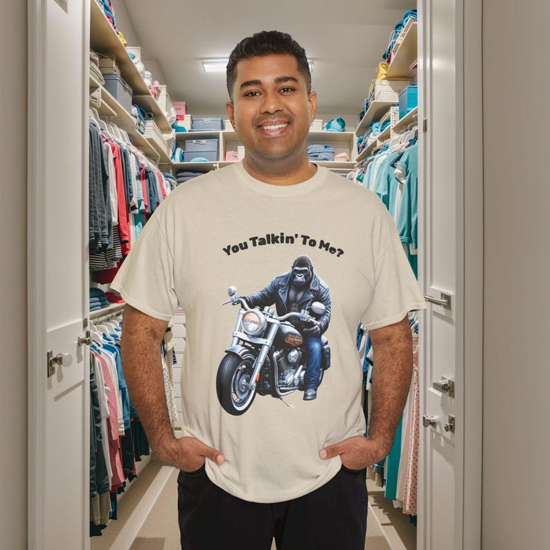 K&ouml;nnte beinhalten: Beiges T-Shirt mit einem Gorilla auf einem Motorrad und dem Text "You Talkin' To Me?". Das Design verwendet Schwarz, Grau und Blau. Dieses l&auml;ssige T-Shirt ist f&uuml;r den Alltag geeignet.