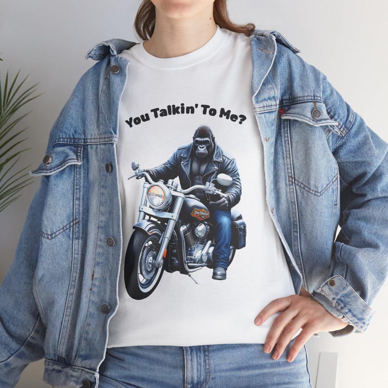 K&ouml;nnte beinhalten: Wei&szlig;es T-Shirt mit einem Gorilla auf einem Motorrad, mit dem Text "You Talkin' To Me?". Der Gorilla tr&auml;gt eine schwarze Lederjacke und blaue Jeans. Das Motorrad ist schwarz mit Chromdetails.