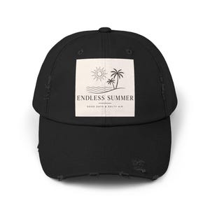May include: Black distressed baseball cap with a square graphic featuring a sun, palm trees, and the words "ENDLESS SUMMER" and "GOOD DAYS & SALTY AIR". The cap has a curved brim and a distressed look.