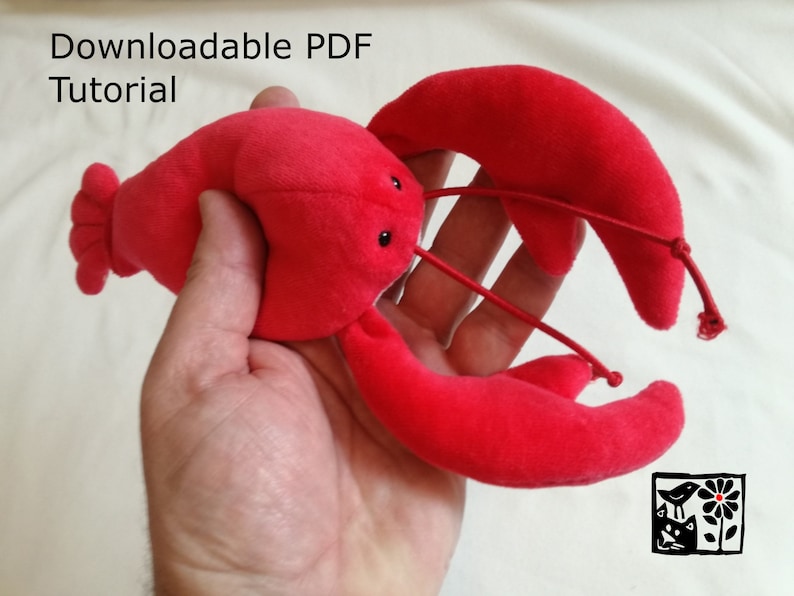 May include: A red plush lobster toy with black eyes and a downloadable PDF tutorial. The lobster is being held in a person's hand.