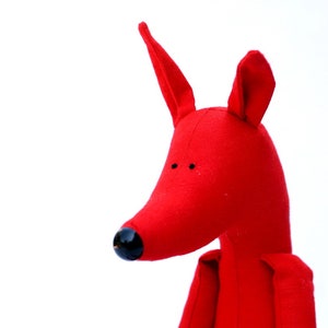 May include: A red fabric toy shaped like a fox with black eyes and a black nose.