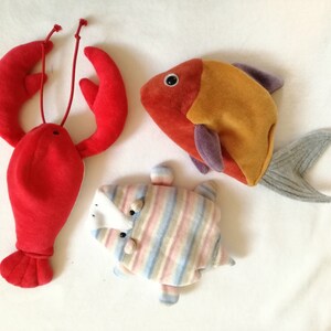 May include: Three plush toys: a red lobster, a striped fish, and an orange and purple fish.