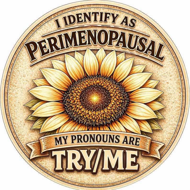 May include: A round, tan-colored graphic with a sunflower in the center. The text "I IDENTIFY AS PERIMENOPAUSAL" arches across the top. Below the flower, a banner reads "MY PRONOUNS ARE TRY/ME."