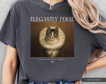 May include: A pepper-coloured t-shirt with a vintage portrait of a cat in a ruffled collar, with the words "ELEGANTLY FERAL" above the image. The text "The Widow" and "CATS & ART - T-SHIRT" are below the image.