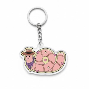 May include: A pink snail-shaped keychain with a cowboy hat and purple bandana. The snail has a light pink body with heart and star details. The keychain is attached to a silver metal ring and chain.