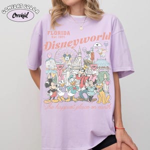 Peut inclure: T-shirt lilas Comfort Colors avec un motif de Disney World en Floride. Le motif comprend Mickey Mouse, Minnie Mouse, Donald Duck et d'autres personnages. Le texte sur le t-shirt indique "Florida Est. 1971 Disneyworld" et "The happiest place on earth."