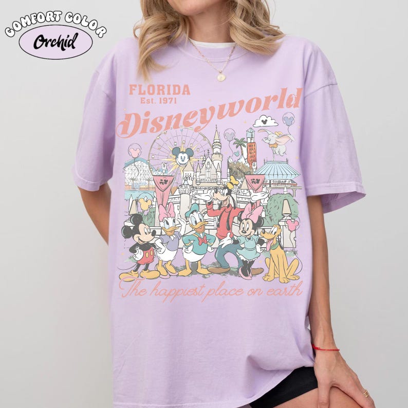Peut inclure: T-shirt lilas Comfort Colors avec un motif de Disney World en Floride. Le motif comprend Mickey Mouse, Minnie Mouse, Donald Duck et d'autres personnages. Le texte sur le t-shirt indique "Florida Est. 1971 Disneyworld" et "The happiest place on earth."