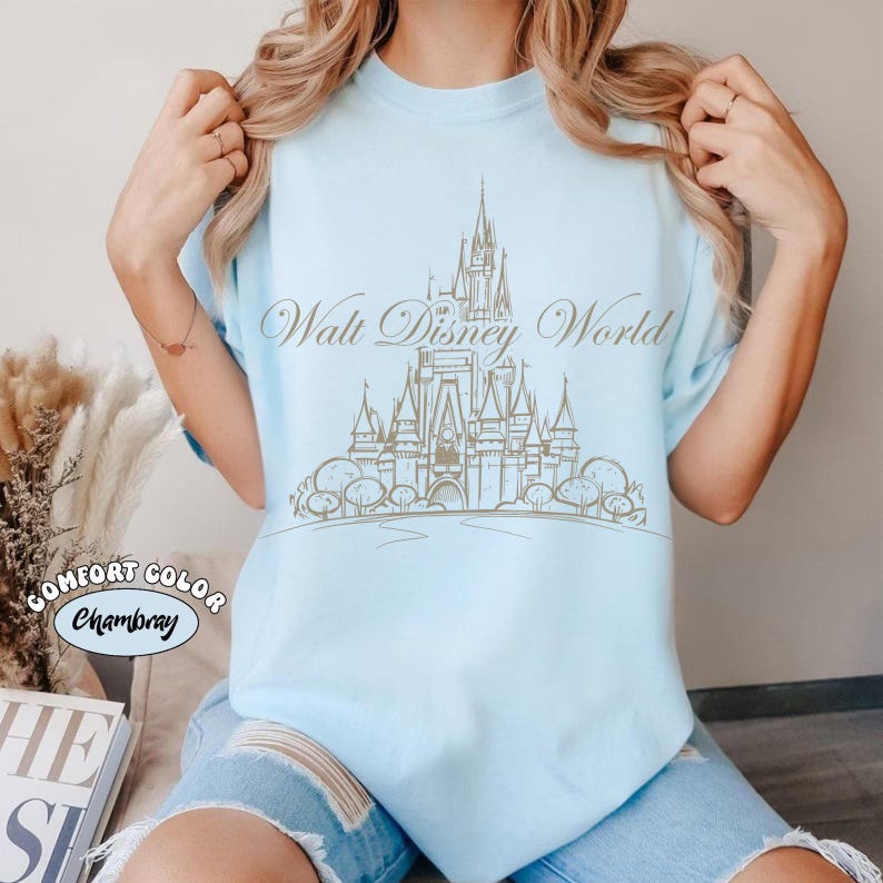 K&ouml;nnte beinhalten: Eine wei&szlig;e Keramik-Tasse mit schwarzem Henkel und dem Text "But First, Coffee" in fetter, schwarzer Schrift. Die Tasse steht vor einem verschwommenen Hintergrund, der eine gem&uuml;tliche Umgebung suggeriert.