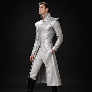 Könnte beinhalten: Ein silberner langer Mantel mit hohem Kragen und Schulterakzenten. Der Mantel hat einen Reißverschluss und wird mit einer passenden hellgrauen Hose und schwarzen Stiefeln kombiniert. Das Outfit ist ein futuristisches Design.
