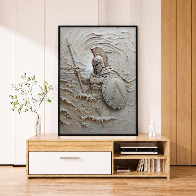 May include: A framed wall art piece featuring a textured, monochromatic relief sculpture of a Spartan warrior in a helmet, holding a spear and a shield with a lambda symbol, emerging from swirling, wave-like patterns in shades of off-white and cream.