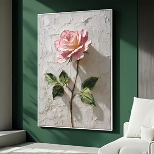 May include: A framed artwork featuring a textured, three-dimensional rose. The rose is a soft pink with yellow highlights, set against a textured white background. Green leaves and a brown stem complete the floral composition.