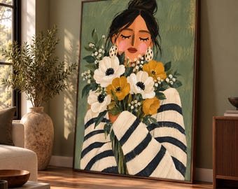 May include: A framed wall art print depicting a person with dark hair in a bun, wearing a cream and navy blue striped sweater, holding a large bouquet of white and yellow flowers against a muted sage green background.